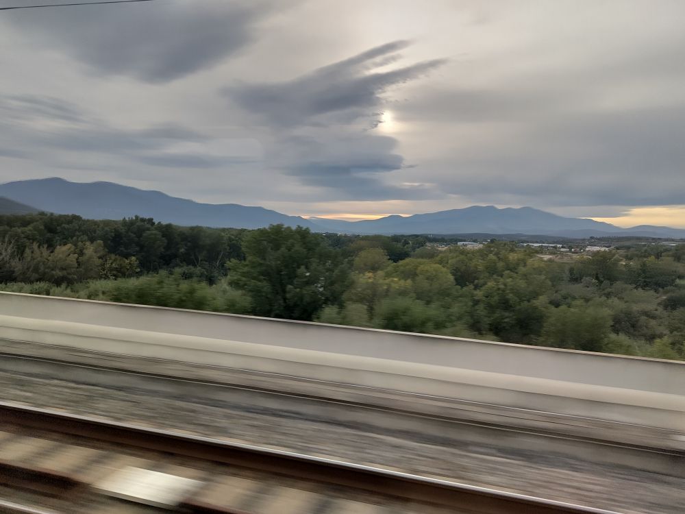 View from the fast moving train, French pyrenees in the background. Slightly gloomy grey sky