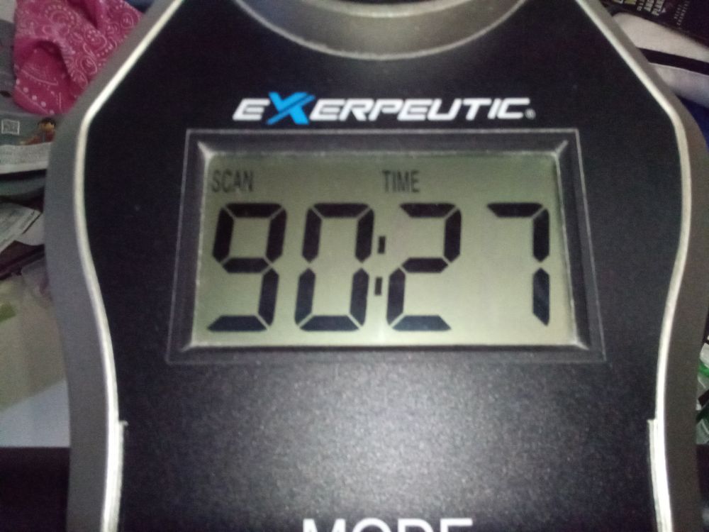 The time elapsed display on an Exerpeutic stationary bike reads 90 minutes and 27 seconds.