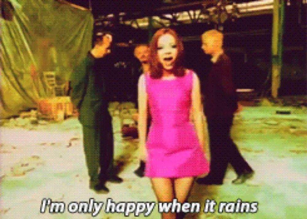 a woman in a pink dress says " i 'm only happy when it rains " in front of a group of people