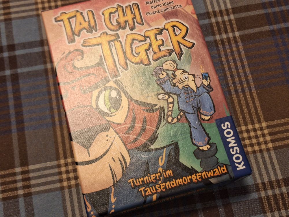 Die Spieleschachtel von Thai Chi Tiger. Darauf sind unter dem Titel als Illustrationen zwei Tiger in blauer Thai-Chi-Kleidung zu sehen. Unten auf der Schachtel steht "Turnier im Tausendmorgenwald".