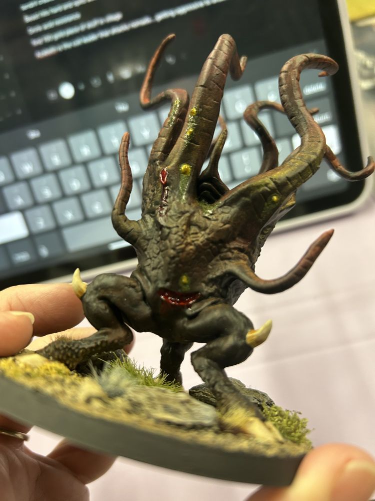 A miniature strange, multi-tentacle Lovecraftian creature with bloody wounds and weeping sores