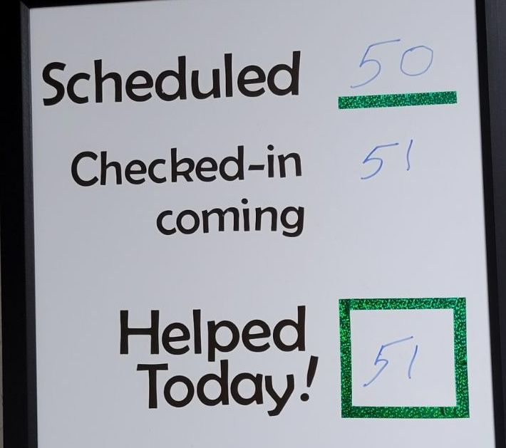 dry erase board listing number scheduled (50) and 51 checked-in/helped today, representing the day's spay/neuter clinic status