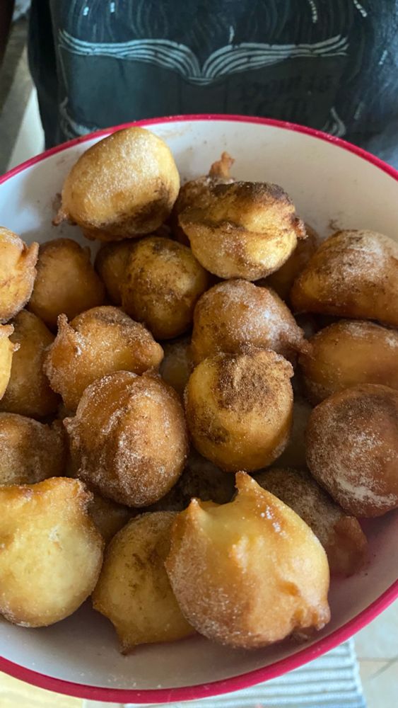 Um pote cheio de bolinhos de chuva com açúcar e canela