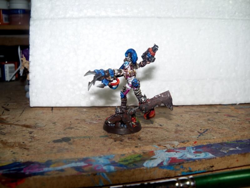 Warwych Druchii, converted Lelith Hesperax figure by Kethmok as a Christmas present around 15yrs ago.  Side on pic showing her Power Klaw and pistol. 

Deep lore part 2

Their fight began with sisters trying to interrupt their duel, while Warriors and Sisters bleed and died around the two battling Drukhari who left a dance of destruction into the gardens of the Chosen temple. Druchii had the upper hand, her years in the arena pushed Haelyndra to her limits, but the duel came to a sudden end when a young Sister of battle charged desperately and distracted Druchii for a heartbeat as she cut down the Human who ignited a grenade as she died destroying Druchii’s right arm and her Sword and throwing her to the ground. In that moment an almost defeated and hurt Haelyndra took advantage and put a Splinter crystal through Druchii’s forehead. 
Leaving Druchii for dead, the Kabal withdrew as an Ork attack swept through the area and left the Temple Gardens in chaos. Sisters returning to find such devastation battled the Orks with a burning fury leaving craters and fire everywhere, but they could not reclaim the temple and vast horde of Orks pushed them back into the next part of the city leaving a vast area around the Temple of littered dead. In this moment a drunken Grotsnik, fabled Mad Doc of the Death Skulls had a vision that led him to the gardens and was drawn to an Ork blood covered body with a hole in the head much like the one he had once repaired on Ghazghkull. He was confused on why they seemed so thin, but trusted his vision and dragged the body to his camp. Creating a new adamantium skull plate he rebuilt the head of the ‘Ork’ and crafted a Power Klaw onto the remains of the right arm. 

Part 3 (last little bit) on next picture.