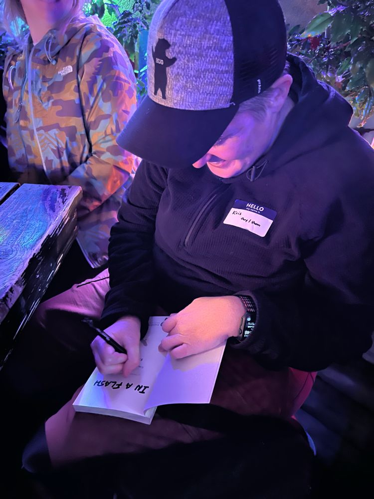 Kris signs a copy of a book titled “In a Flash”.