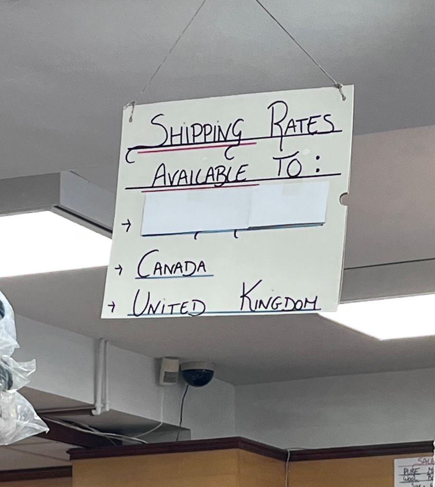 Hand written sign saying “shipping rates available to Canada, United Kingdom”. There is also a line, covered up by paper, that used to read United States. 