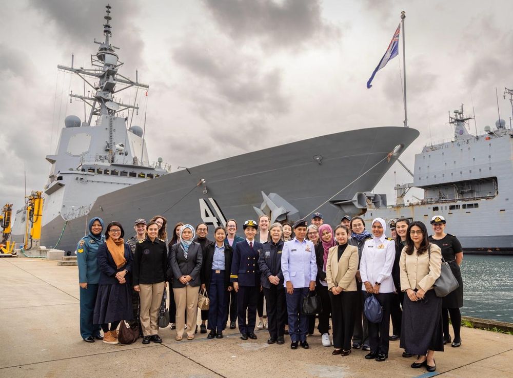 The women of the WIMS program stand in front of a Royal Australian Navy ship at HMAS Kuttabul in Sydney.