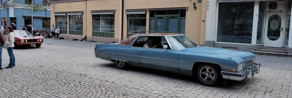 To gamle biler som kjører gjennom gågata i Halden