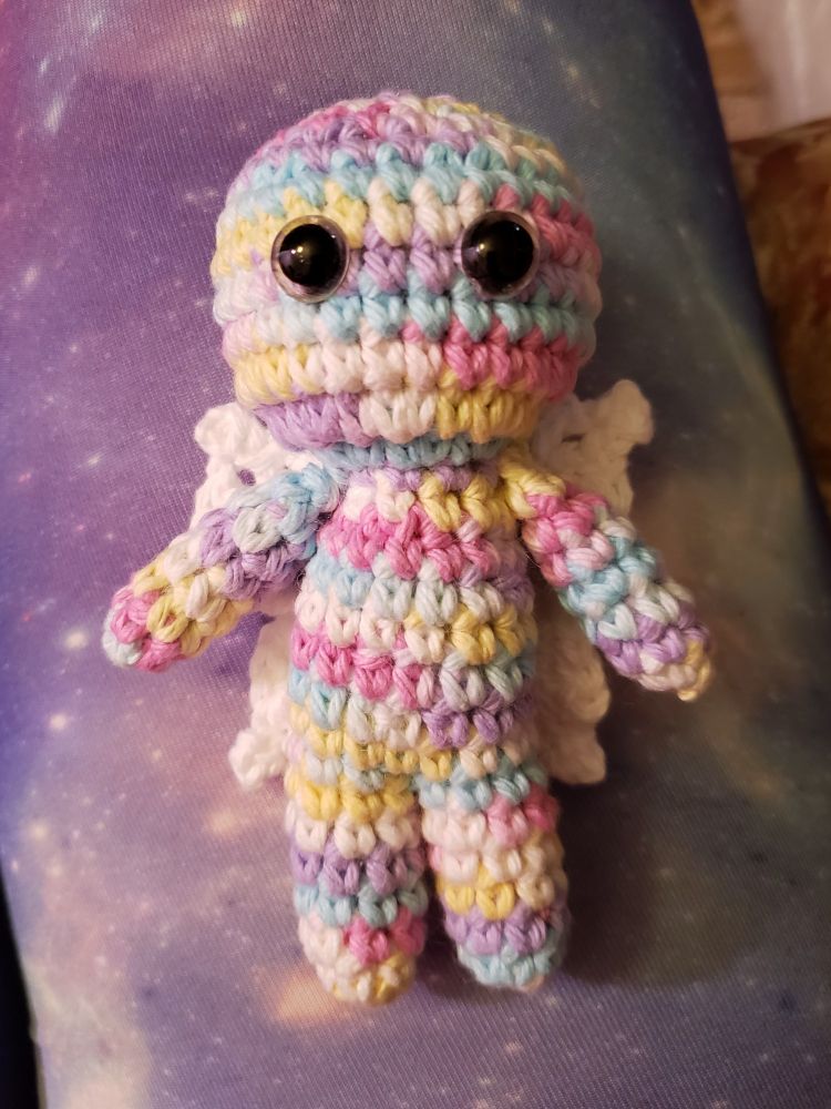 A poppet, also known as a sympathy doll, that I crocheted myself with a pastel rainbow yarn body and white wings.