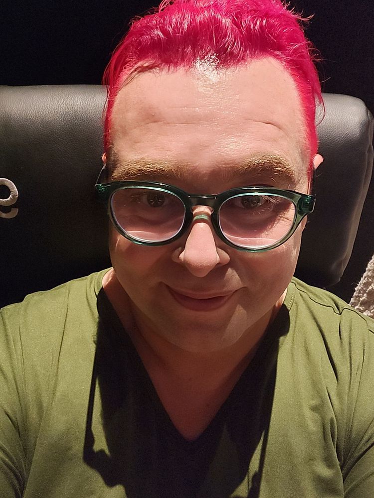 Pink haired transwoman in a movie seat.