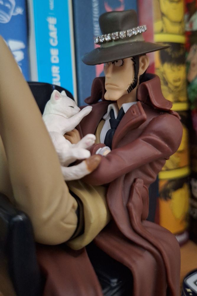 Picture of a figure of Zenigata from Lupin III, which I've added a sleeping cat gashapon figure on top of his body and a strass ring over his hat.