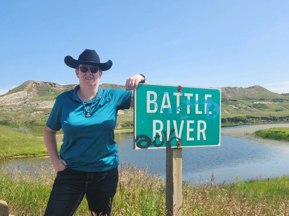 Bonnie wearing a cowboy hat in a prairie scene with a sign that says Battle River