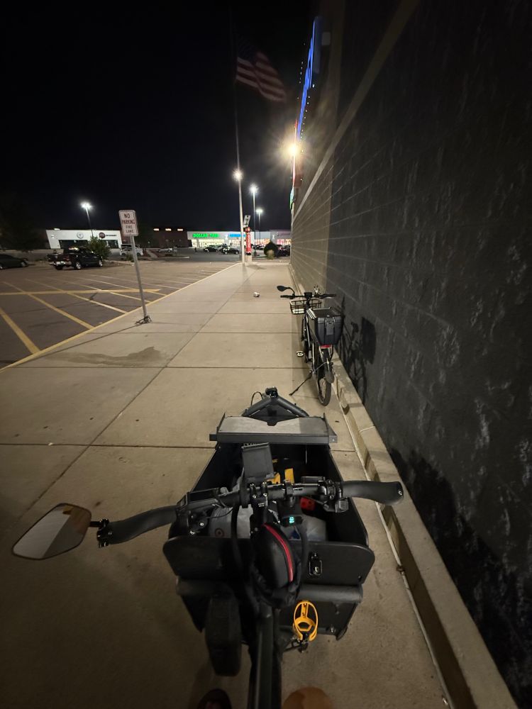 Perspective from sitting on cargo bike looking at another bike parked in front of a store