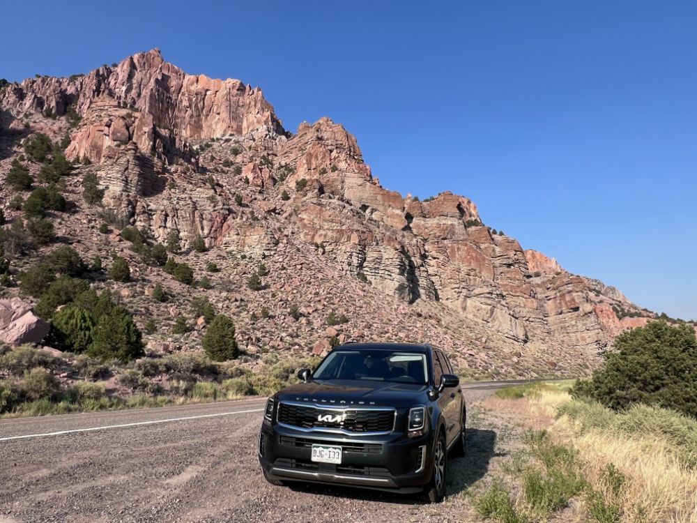 A Kia Telluride on the side of the road in front of some red(ish) rocks near Marysvae, Utah