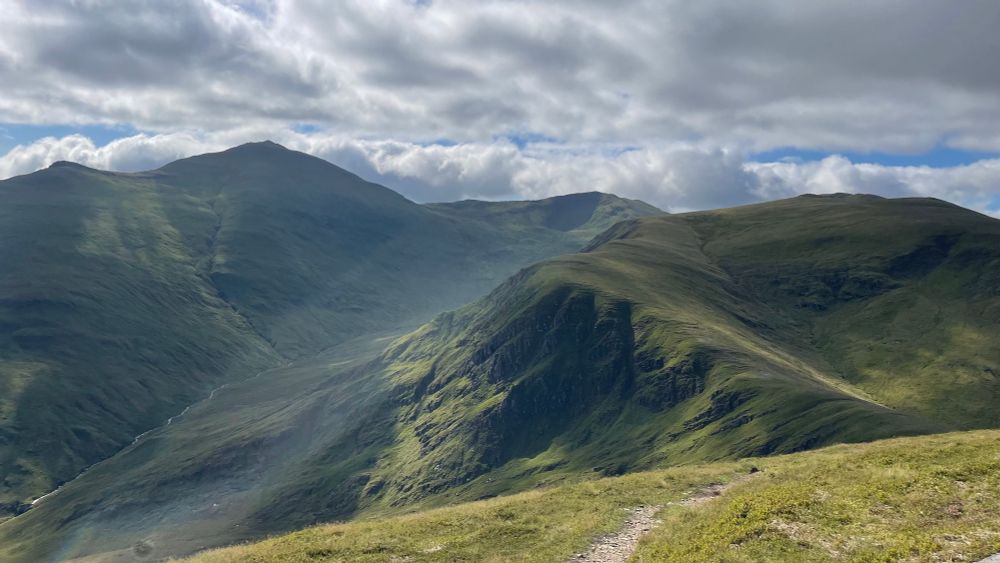 Green mountains with clouds and sun