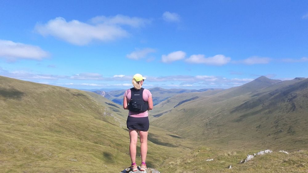 Me in running clothes standing with green mountains behind 