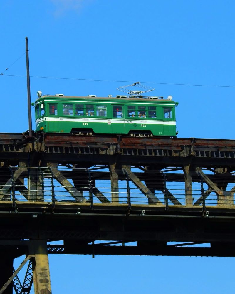 [Image description: Image shows the historical Edmonton trolley crossing the high level bridge with people waving in the windows.]