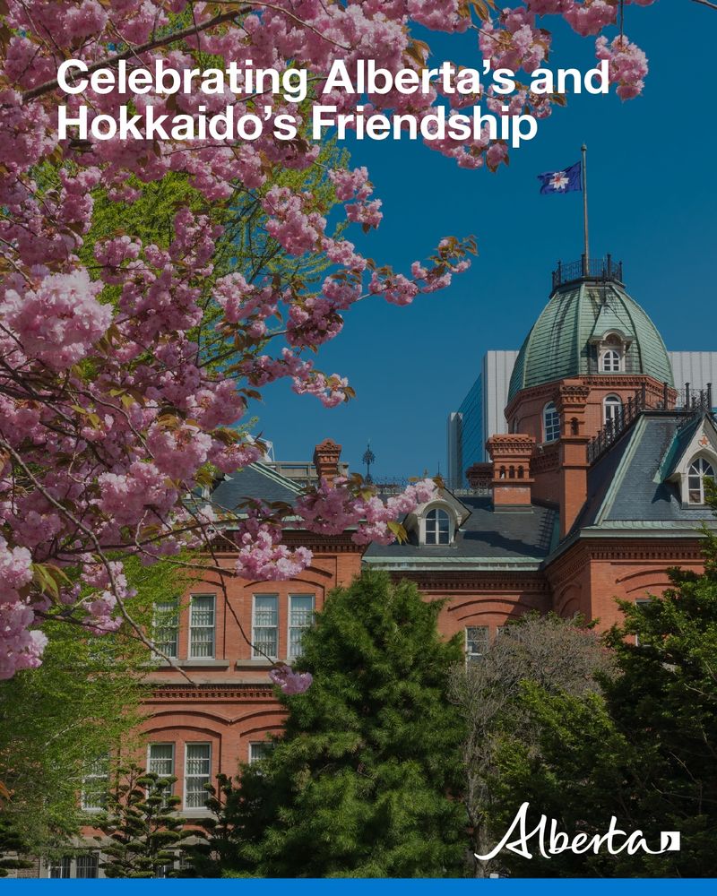 [Image description: Image shows a retired historic government building in Hokkaido, Japan surrounded by cherry blossoms in spring. Text reads, celebrating Alberta and Hokkaido’s Friendship, with white Alberta logo in bottom corner.]