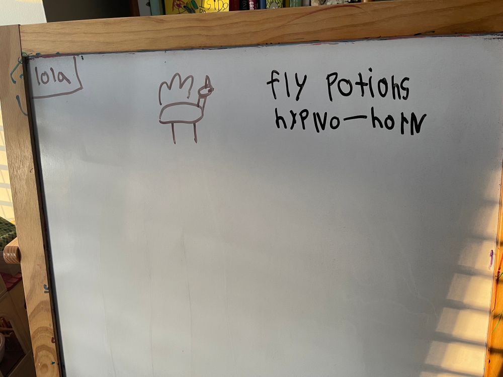 Whiteboard drawing of a winged unicorn noting “fly, potions, hypno-horn” in 7-year-old’s handwriting