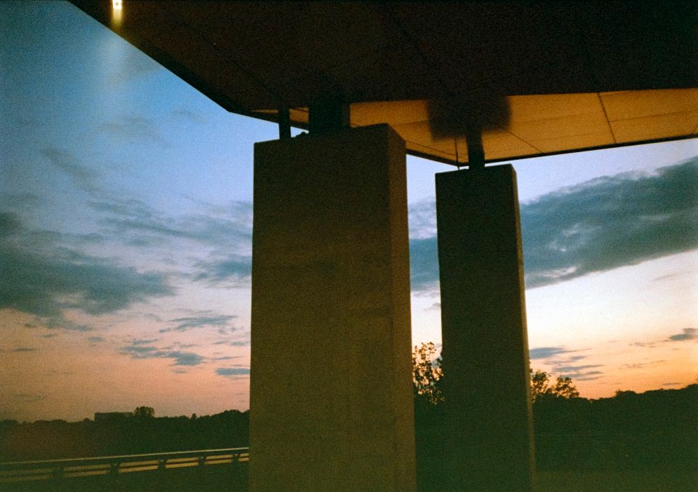 two concrete pillars holding up.a roof at sunset