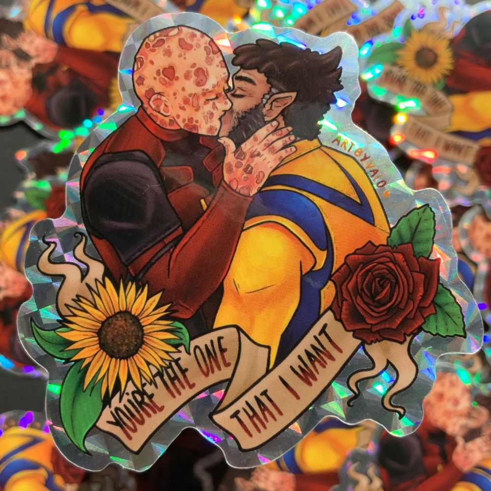 sticker design of deadpool and wolverine kissing. text reads “you’re the one that i want”