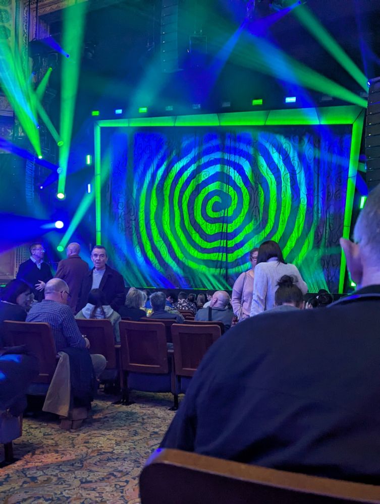 Theater stage with hypnotic spiral and blue and green spotlights. 