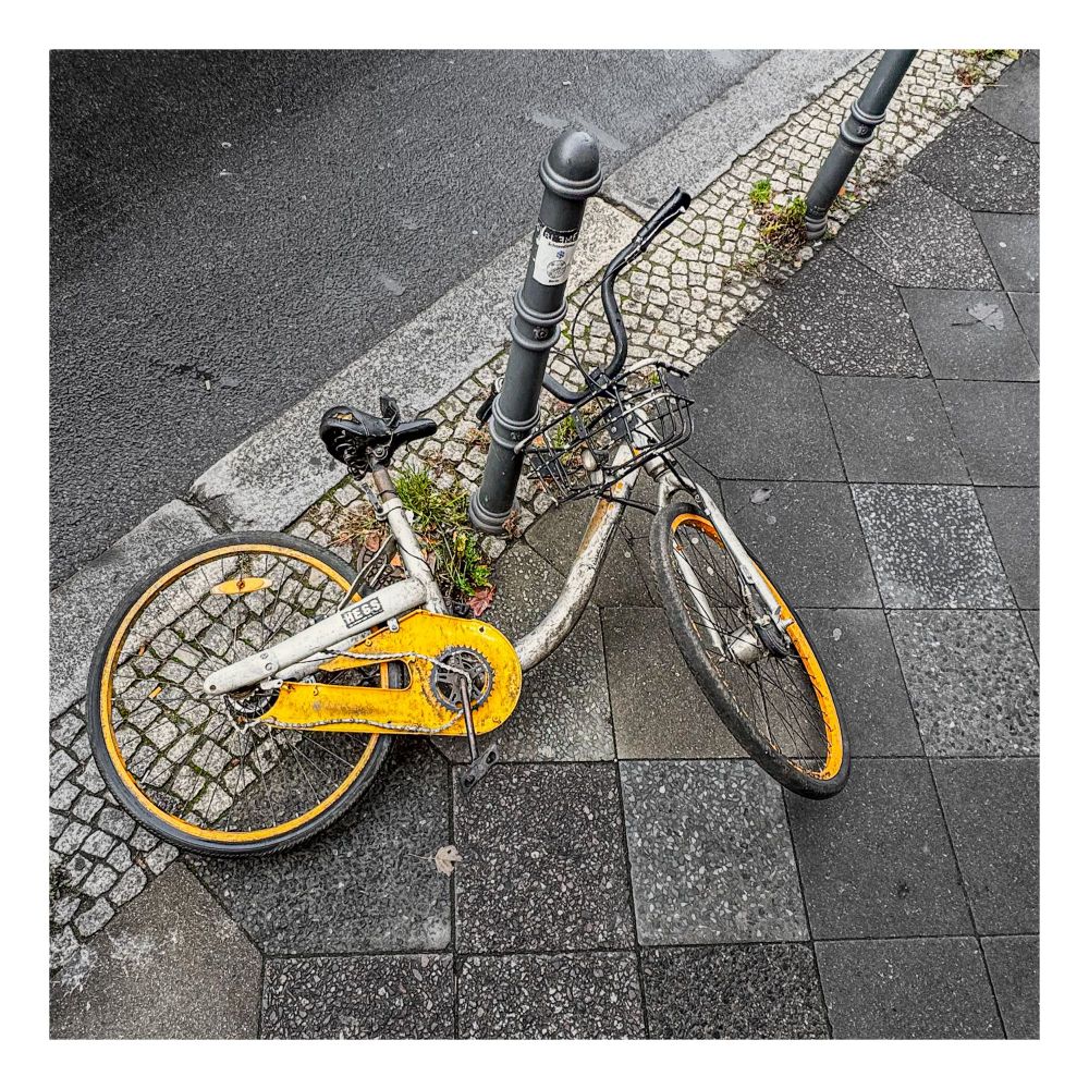 A yellow and white bicycle lies crumpled on the ground, its chain guard off and chain off the main pedal cog.