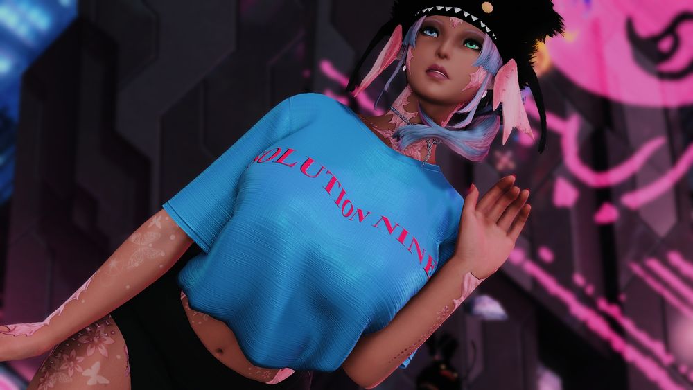 Sylari standing in front of a wall in Solution 9, wearing a blue loose, shirt that leaves her belly exposed, and a short skirt. 