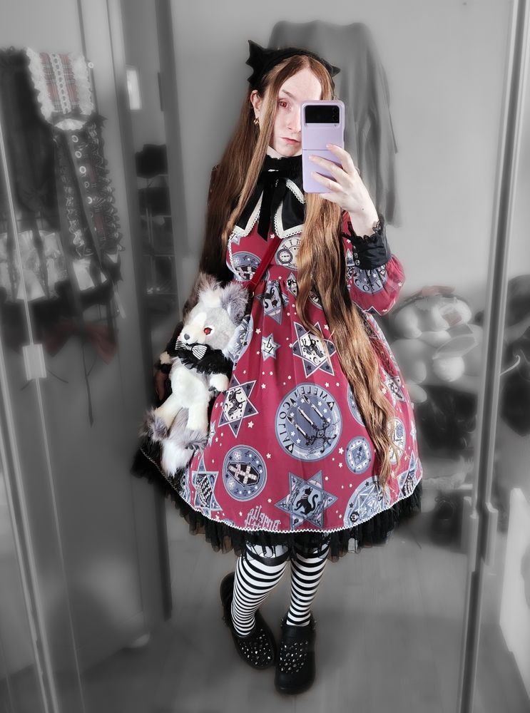 Mirror selfie while wearing:
Black velvet bat cat Antique Beast headdress
Red contact lenses
Loose natural face framing red hair, which is almost knee length
Magic Amulet OP in the red colourway by Angelic Pretty
Captain Chris "blood" with red eyes
Black and white horizontally striped tights
Black platform Crocs covered in studs