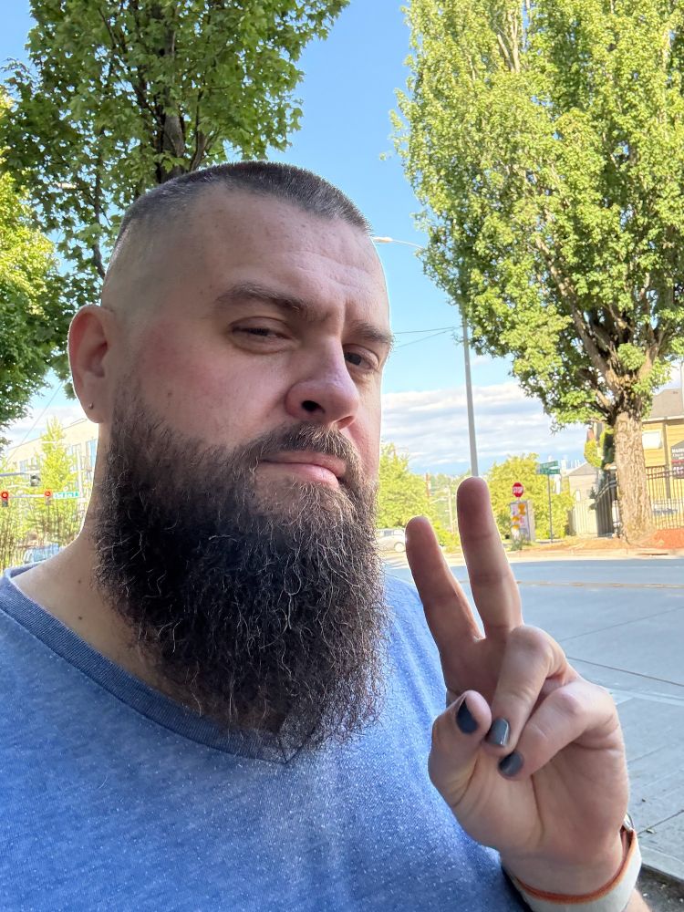 Bearded man with painted nails flashing a ✌️