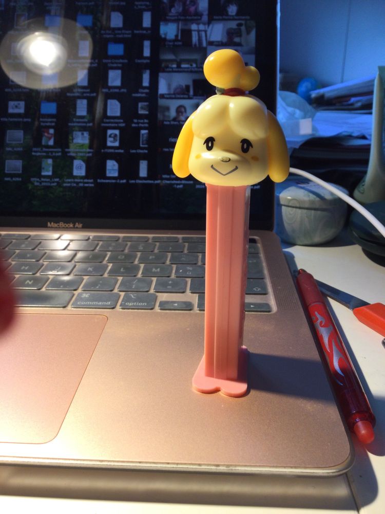 A pink and yellow candy dispenser with the head of what looks like a poodle. 