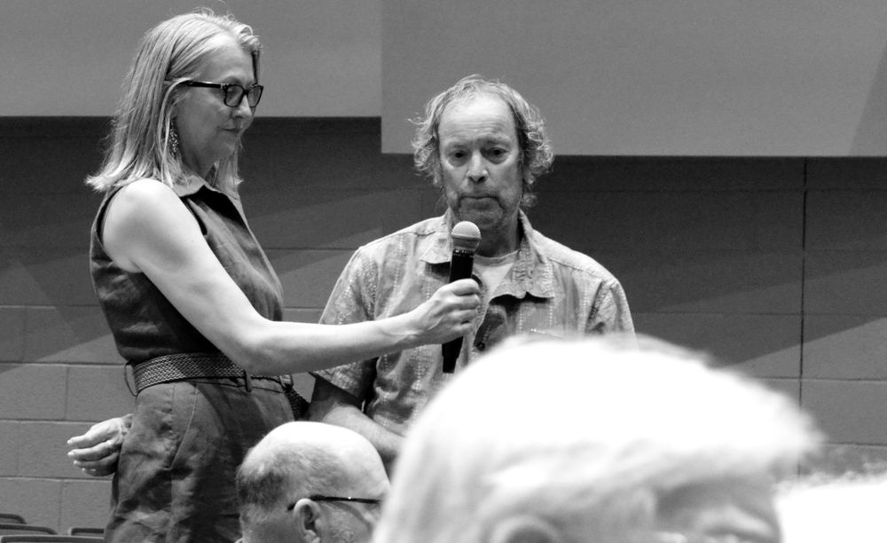 A gentleman asking a question into a microphone held by one of Senator Wyden's support staff