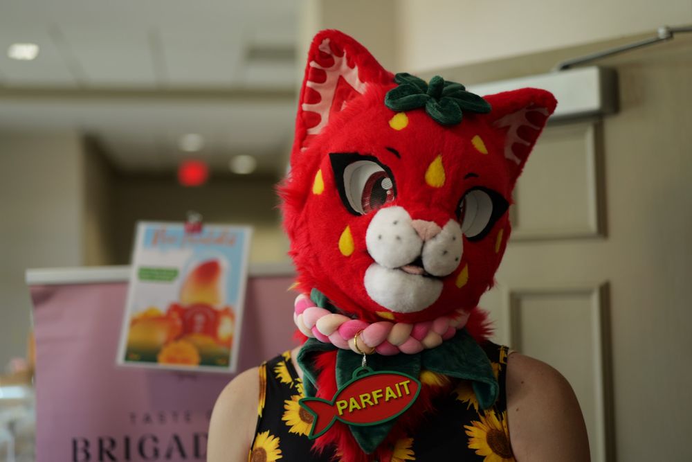 A feline fursuiter themed with strawberry colors.