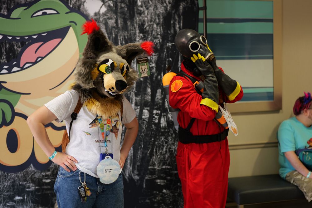 A canine fursuiter and a cosplayer posing for pictures at chomp.