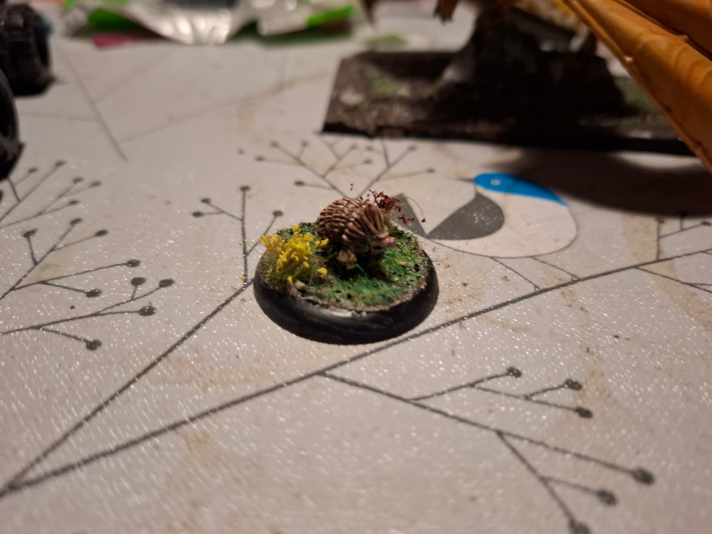 Brown hedgehog on a grassy base with flowers 