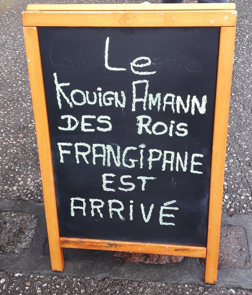 Photo d'un petit panneau de boulangerie avec noté dessus : "Le Kouign Amann des Rois frangipane est arrivé"