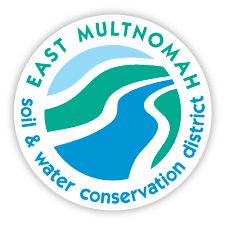 A round logo featuring stylized blue and green curves, representing flowing water and rolling hills. Above the curves, the text reads 'EAST MULTNOMAH' in bold capital letters. Below the curves, the text says 'soil & water conservation district' in smaller capital letters. The overall color scheme is shades of blue and green on a white background.