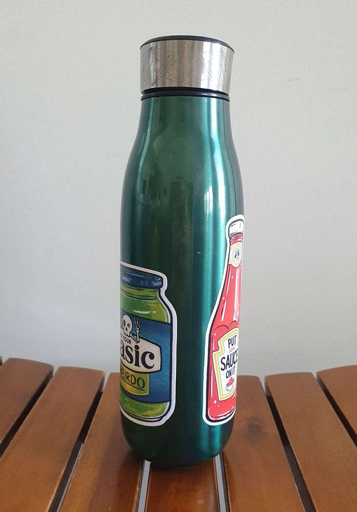 A green metal tea thermos with stickers.