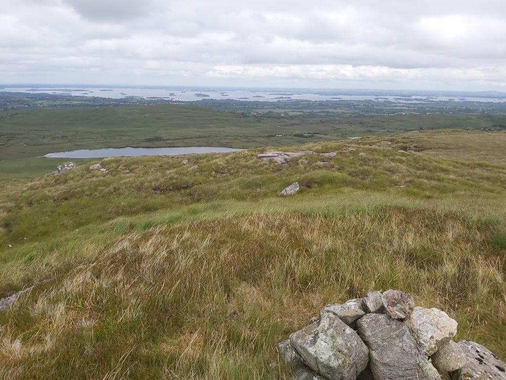 Blick von Clooshgereen auf Lough Corrib. Die Straße führt von Oughterard zum Windpark und dann weiter zur östlichen Atlantikküste bei Derroe.