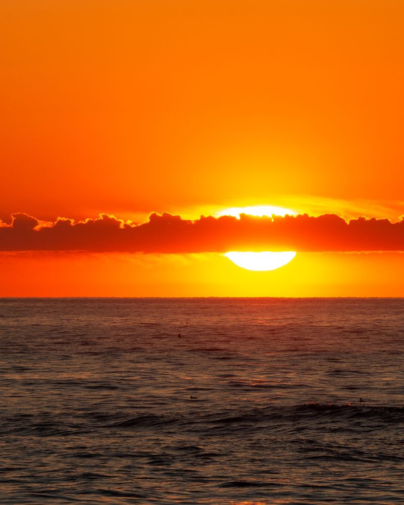 Sunrise over the Gulf of Maine, in New Hampshire. The sky is bright orange and red, with a calm ocean beneath. 