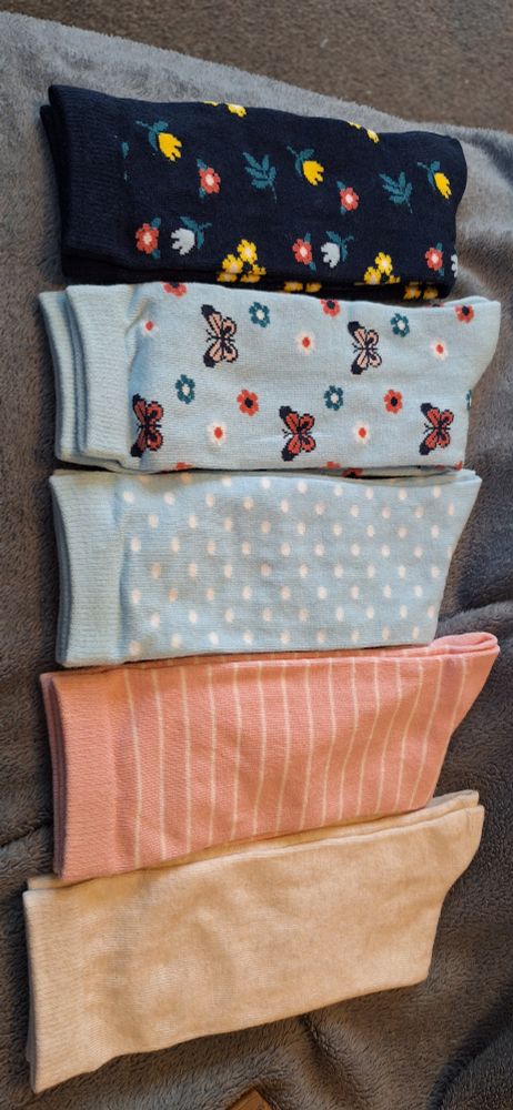 An array of lovely soft socks, from a navy floral pair, light blue pair with flowers and butterflies, a light blue poolkadot pair, a pink stripe pair and a plain pale pink.
