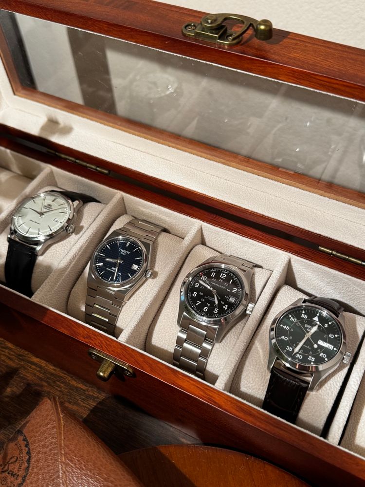 White Orient bambino v7, blue tissot prx 80 automatic, Hamilton khaki field auto with bracelet, and seiko 5 sports automatic green dial watches in a walnut watch case. 