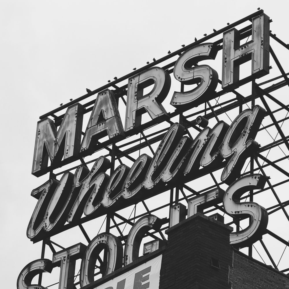 Birds lined up on a building sign that reads “marsh wheeling stogies”