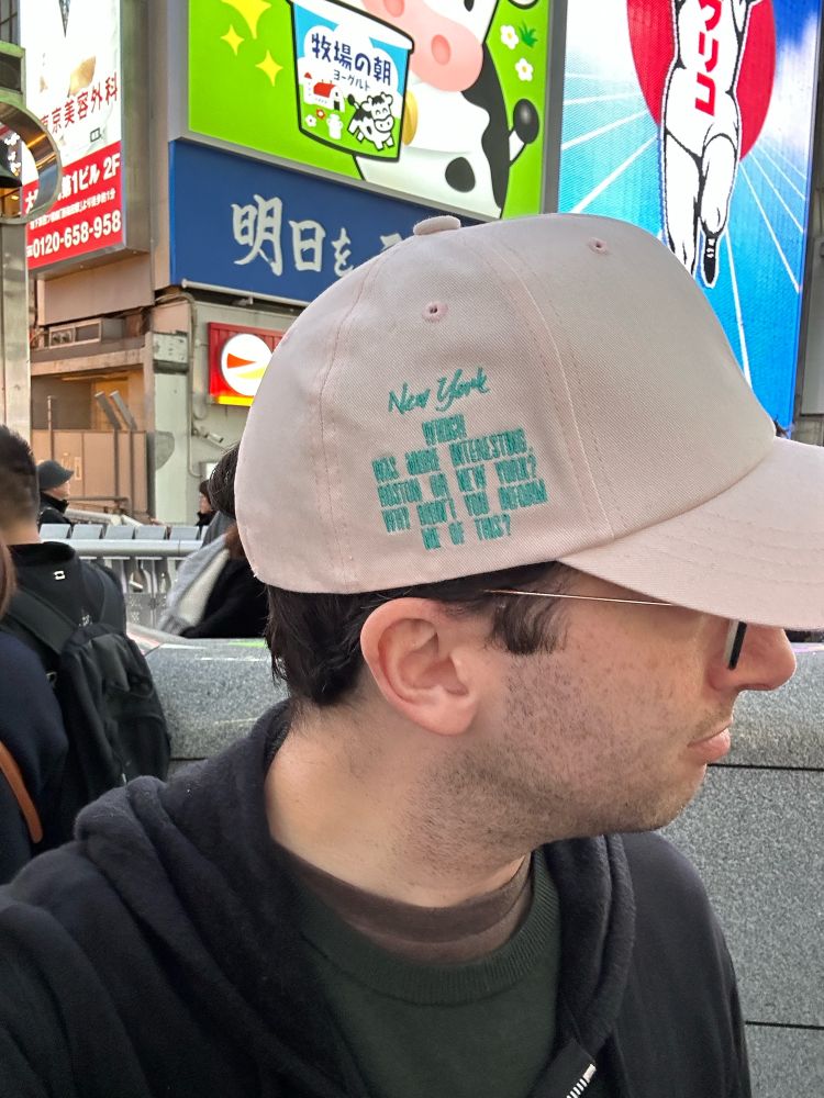 The side of the hat says “Which was more interesting, Boston or New York? Why didn’t you inform me of this?”