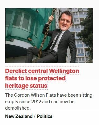 Screencap of the Radio NZ homepage thumbnail for its story titled 'Derelict central Wellington flats to lose protected heritage status' features an image of Housing Minister Chris Bishop's head photoshopped on top of a thin man in a business suit riding a construction wrecking ball superimposed over the Gordon Wilson Flats in Wellington.