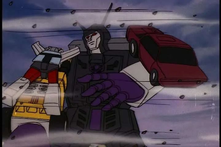 captura de pantalla de la serie Transformers G1
Menasor aparece en plano americano, mirando a Bluestreak, quien se sostiene a su brazo derecho, e intenta agarrarlo con su mano izquierda.
Un viento violento los rodea. 