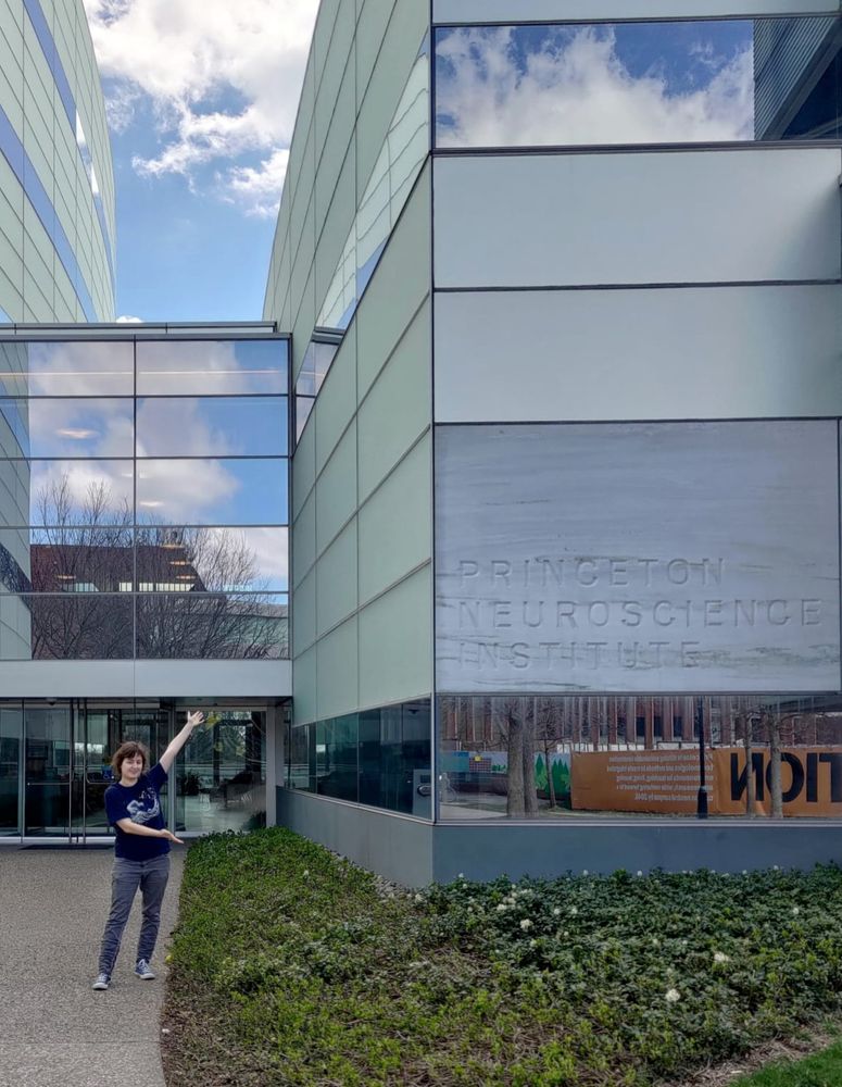 The poster is standing in front of the Princeton Neuroscience Institute and pointing at the sign.