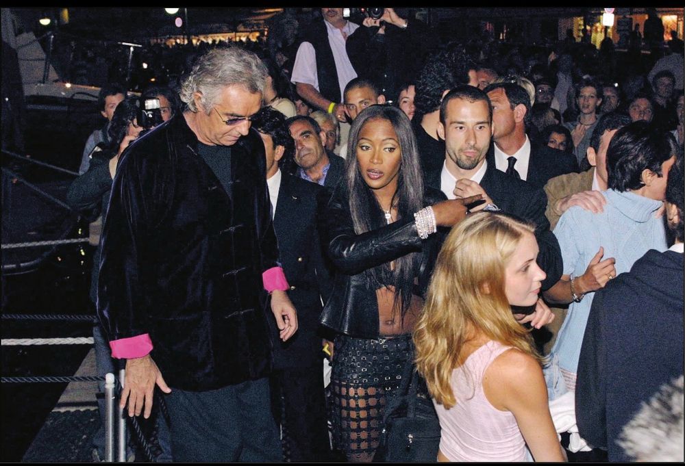 Virginia Giuffre, then 17, in a pink tank top in the bottom right corner. Center is Naomi Campbell pointing to the right. Next to her are some older men and a body guard. Ghislane Maxwell can be seen in the right corner behind Virginia 