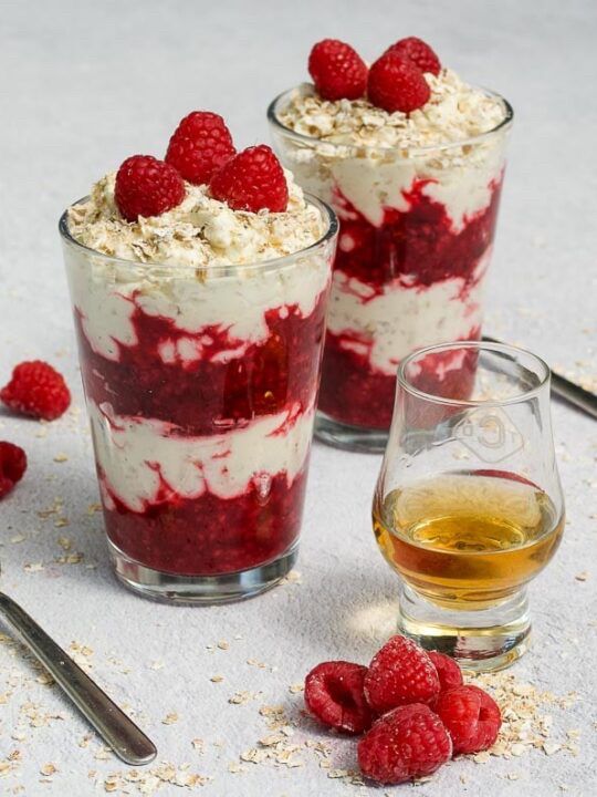 Raspberry and cream dessert with oats and a glass of whiskey.