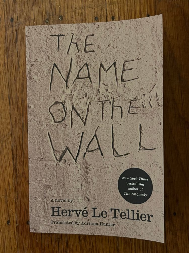 Cover of the Other Press edition of The Name on the Wall, written by Hervé Le Tellier and translated by Adriana Hunter.
It features an illustration with the words The Name on the Wall carved into a wall.